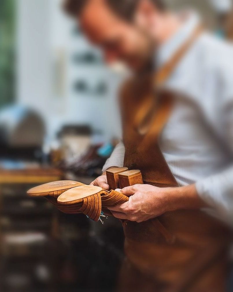 Mains d'un cordonnier tenant des formes en bois à l'atelier